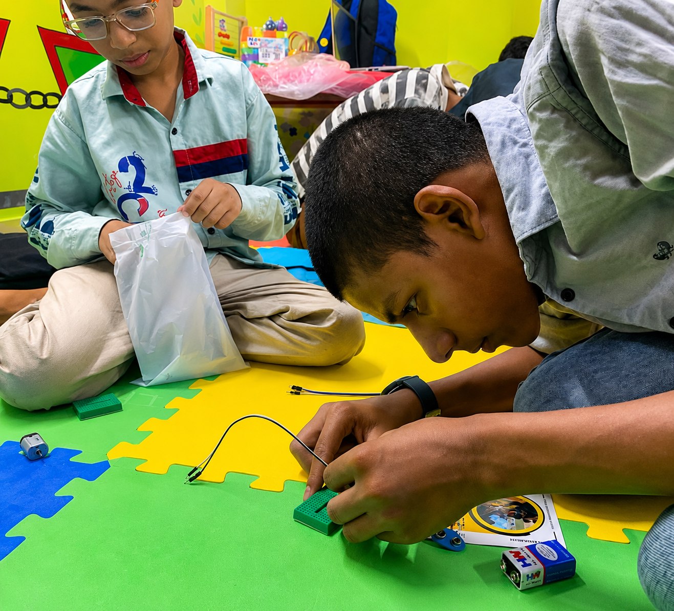 Students carefully connecting components on a small breadboard circuit